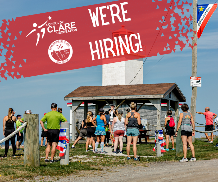 A group of people gathered in front of the Cape St. Mary's lighthouse before the Cape-to-Cliff beach run with the text "We're hiring!"